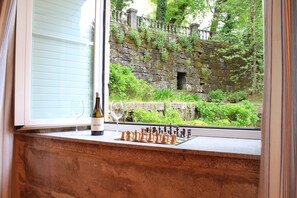 A chessboard on a window ledge with a bottle and glass of wine.