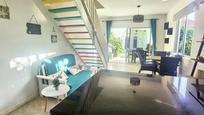 Ein modernes Wohnzimmer mit einem blauen Sofa, einem Couchtisch und einer Treppe mit bunten Stufen.