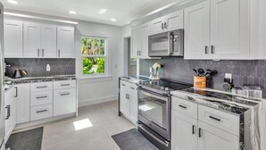 A modern kitchen with white cabinetry, a built-in oven, and a microwave. - Historic Waterfront 3/2 With Yard & Soaking Tub (Lake Worth)