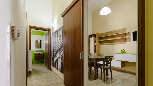 A hallway leading to a dining area with a table and chairs, a radiator, a green wall, and a framed picture on the wall. - Grandma Cecilia's terrace (Lecce)