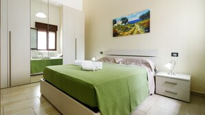 A bedroom with a bed, a nightstand, a bedside lamp, a painting, and a window. - Grandma Cecilia's terrace (Lecce)