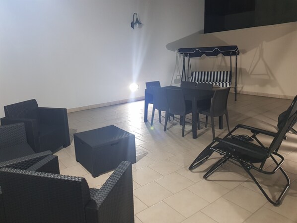 Una habitación con una mesa de comedor y sillas, un sofá y una silla colgante.