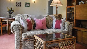 A living room with a patterned sofa, a glass coffee table, a wooden cabinet, and wall-mounted lamps. - 1 bedroom accommodation in Pickering (Pickering)