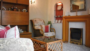 A traditional room with a fireplace, a wooden chair, a glass table, and a bed with patterned bedding. - 1 bedroom accommodation in Pickering (Pickering)