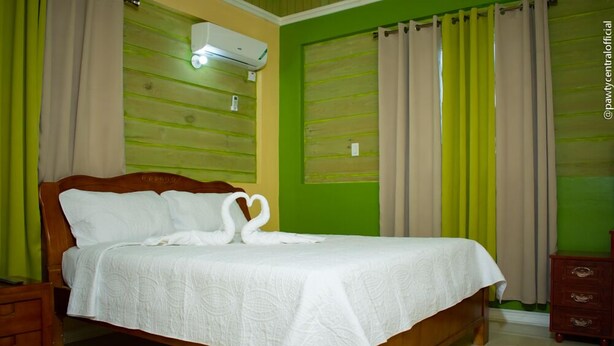 A neatly made bed with a white bedspread and a swan-shaped pillow arrangement. - Incognito Vacation Stay (Kingston)