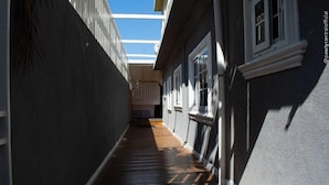 A narrow hallway with wooden flooring, a skylight, and a view of a room with a window. - Incognito Vacation Stay (Kingston)