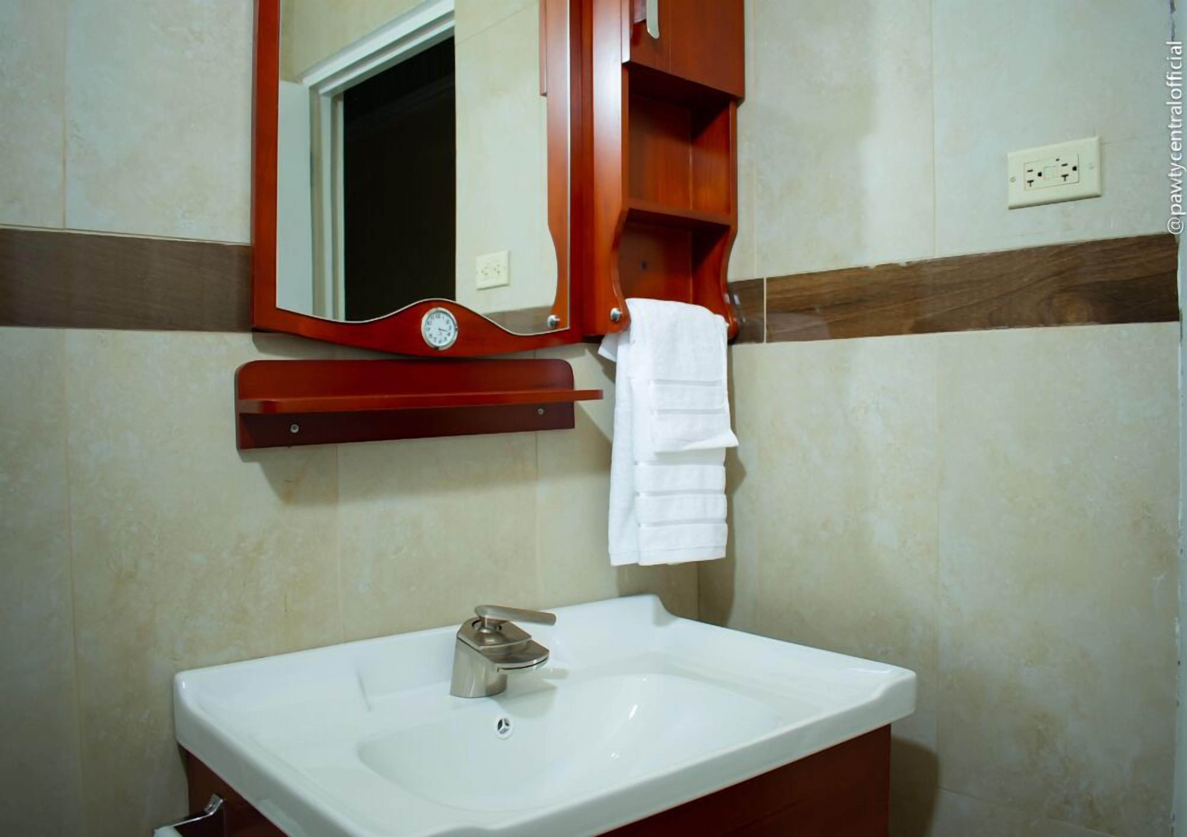 Un baño con un lavamanos blanco, un espejo y un armario de madera para medicinas.