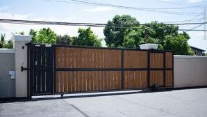 A gated area with a concrete floor, a wooden fence, and a black gate. - Incognito Vacation Stay (Kingston)