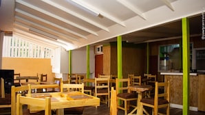A restaurant with wooden tables and chairs, a high ceiling with skylights, and a kitchen area visible through an open partition. - Incognito Vacation Stay (Kingston)