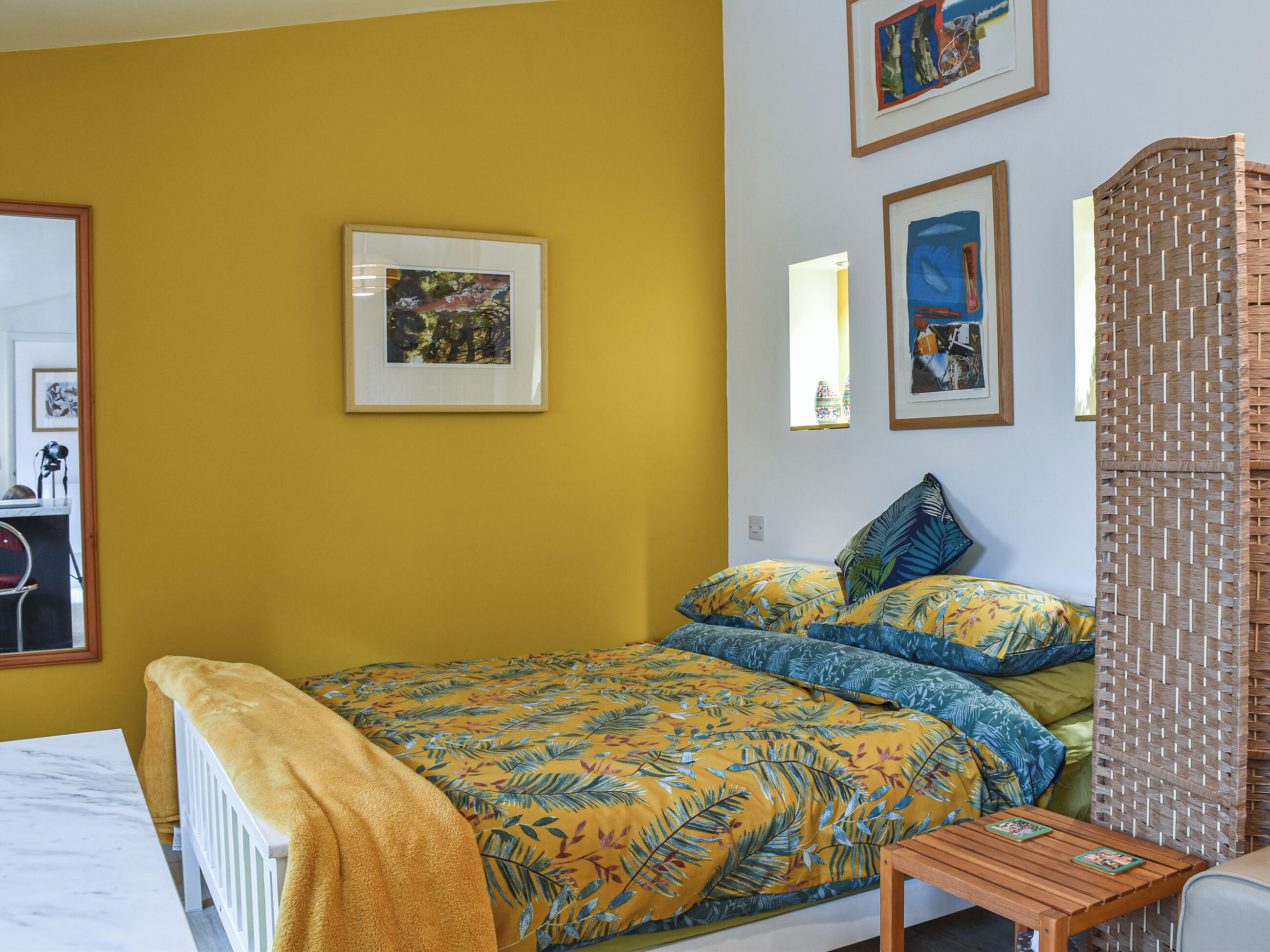 A bedroom with a bed, a wooden nightstand, and a small table.