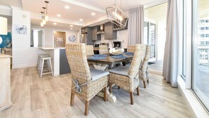 A modern kitchen with a dining area featuring wicker chairs and a wooden table. - Luxury Living from the 9th Floor of Silver Shells (Destin)