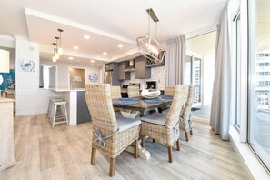 A modern kitchen with a dining area featuring wicker chairs and a wooden table. - Luxury Living from the 9th Floor of Silver Shells (Destin)