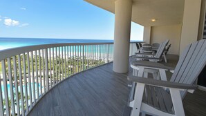 A balcony with a view of the ocean, white chairs, and a pool. - Luxury Living from the 9th Floor of Silver Shells (Destin)