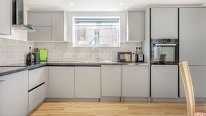 A modern kitchen with grey cabinets, a black countertop, and a window above the sink.