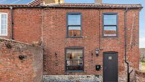 A brick building with two windows, a door, and a small garden area with gravel.