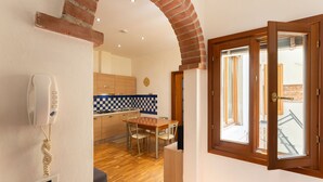 Une cuisine avec un mur recouvert de carreaux à motifs, une table en bois et un téléphone fixé au mur.