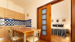Une cuisine compacte avec un dosseret à carreaux, des armoires en bois et un coin repas comprenant une table et des chaises en bois.