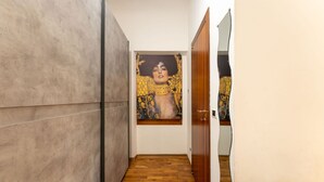 Un couloir doté d’un plancher en bois, d’un grand tableau abstrait accroché au mur et d’une porte en bois.