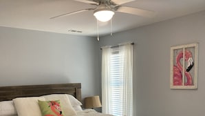 A bedroom with a wooden bed, a ceiling fan, and a window with blinds. - Built in 2021, Cute cottage short walk to beach (Oak Island)
