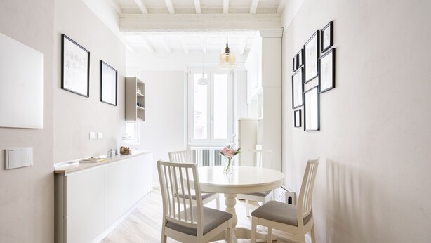 A dining area with a round table, white chairs, and framed pictures on the walls.