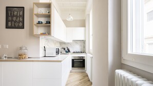 A modern kitchen with white cabinetry, a marble backsplash, and a built-in oven.
