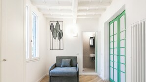 A hallway with a grey sofa, a green door, and a framed artwork on the wall.