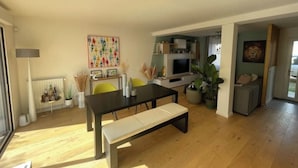 A modern living room with a wooden floor, a dining table with chairs, a bench, a TV, and a sofa. - Pleasant new house Angers Centre-Madeleine (Angers)