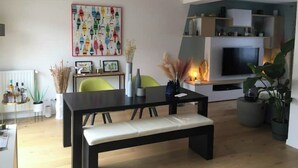 A modern living room with a dining table, chairs, a bench, a TV, and a colorful abstract painting on the wall. - Pleasant new house Angers Centre-Madeleine (Angers)