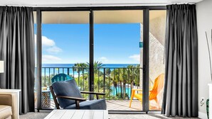 A balcony with a view of the ocean, a pool, and palm trees. - 🏖️Stunning Views of Gulf & Pool | Edgewater 1-305🏖️ (Panama City Beach)