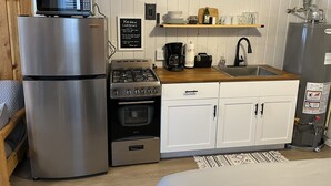 A compact kitchen with a refrigerator, stove, oven, microwave, and sink. There is a sign on the wall and a shelf above the sink. - Cozy cabin #3 in mountains near Rio Grande River (South Fork)