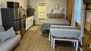 A compact room with a kitchenette, a bed, a small table, and a bench. - Cozy cabin #3 in mountains near Rio Grande River (South Fork)