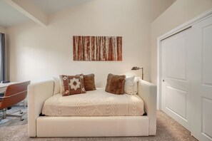 A bedroom with a sofa bed, a desk, and a chair.