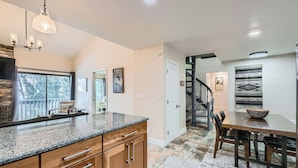 A modern kitchen with granite countertops, wooden cabinets, and a dining area with a table and chairs. - Nicely Updated Property, Steps from In-town Shuttle, Pool (Vail)