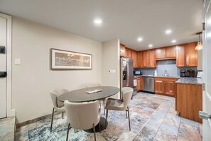 A modern kitchen with wooden cabinets, stainless steel appliances, and a dining area with a round table and chairs.