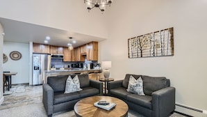 A modern living room with two grey sofas, a wooden coffee table, and a kitchen in the background. - Nicely Updated Property, Steps from In-town Shuttle, Pool (Vail)