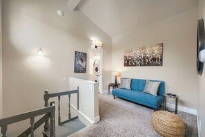 A modern living room with a blue sofa, a coffee table, a lamp, and a painting on the wall.