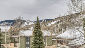 A residential area with houses, a tall evergreen tree, and snow-covered mountains in the background. - Nicely Updated Property, Steps from In-town Shuttle, Pool (Vail)
