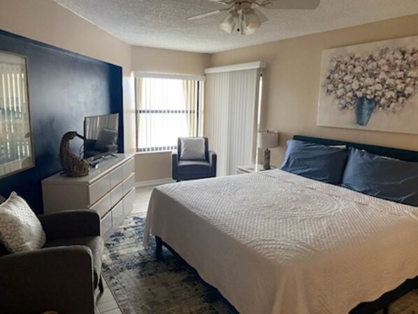 A bedroom with a large bed, a desk, a chair, and a window with blinds. - 3BR/2BA Oceanfront retreat for 6. Spacious, updated, pool,beach & ocean views. (Ormond Beach)