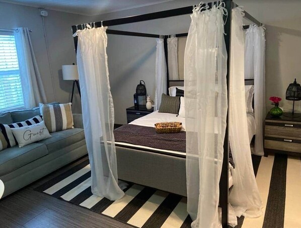 A four-poster canopy bed with a white bedspread and a decorative basket on the nightstand. - "Tropical Oasis" by the beach & shops, with pool (Riviera Beach)
