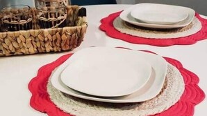 A dining table with white plates and red placemats, surrounded by wicker baskets and a potted plant. - "Tropical Oasis" by the beach & shops, with pool (Riviera Beach)