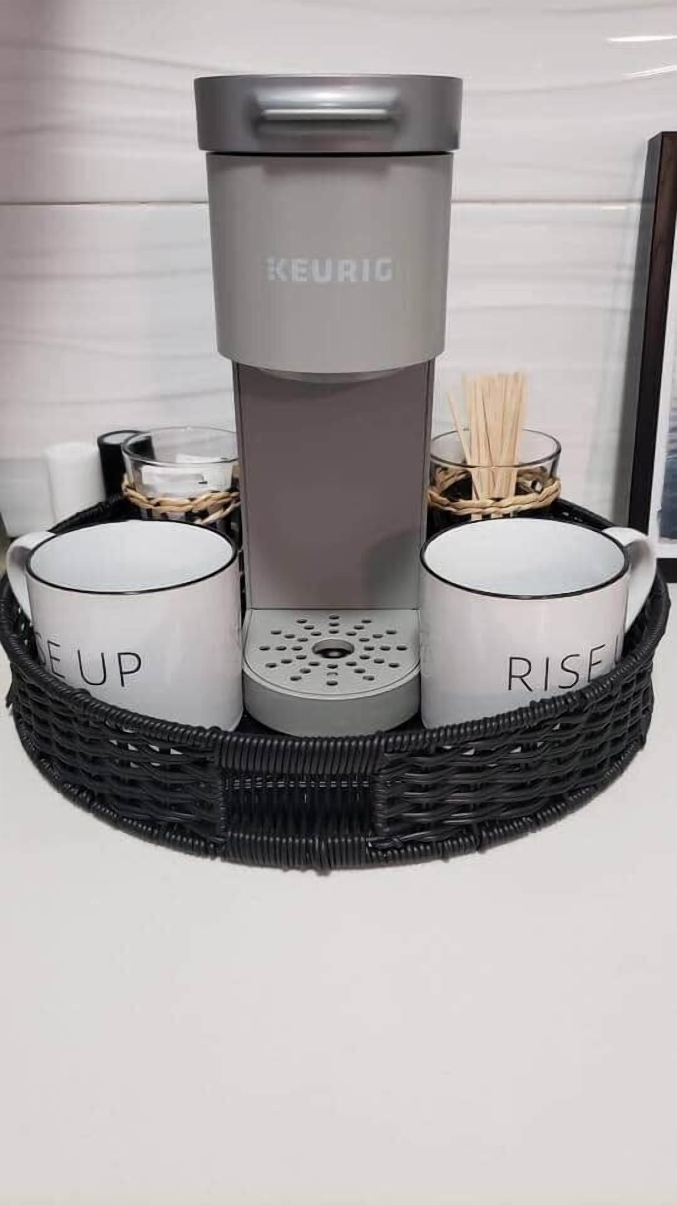A KEURIG coffee maker in a basket with two mugs labeled "ME UP" and "RISE".