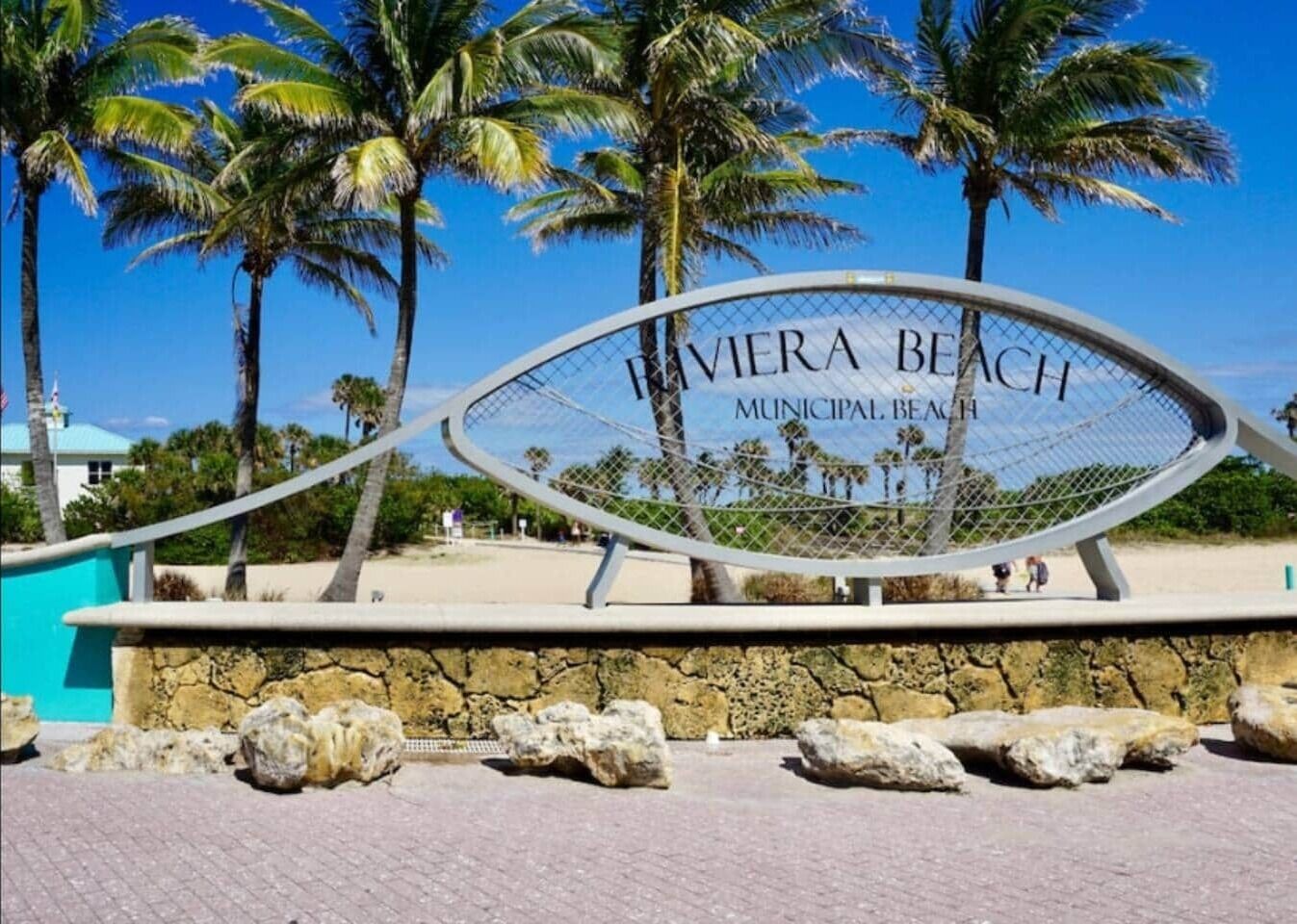 A sign for 'Bieria Beach Municipal Beach' with palm trees and a clear sky in the background.
