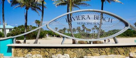 A sign for 'Bieria Beach Municipal Beach' with palm trees and a clear sky in the background.
