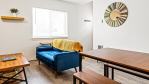 A modern living room with a blue sofa, wooden coffee table, and a dining table. - Modern Downtown Kalispell Getaway — Walk to Coffee, Shops & Breweries (Kalispell)