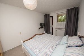 Una camera da letto con un letto, una televisione, una finestra con tende e un soffitto bianco.