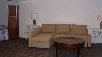Una habitación con un sofá seccional color beige, una mesa de centro de madera y dos mesitas de noche con lámparas.