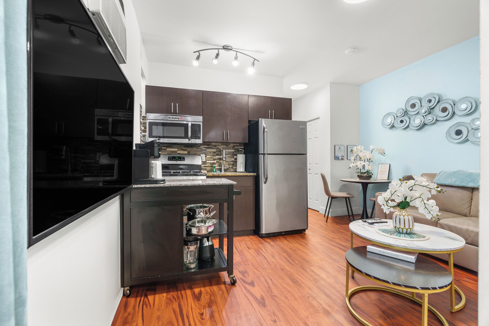 A modern kitchen with dark cabinets, stainless steel appliances, and a small island with a coffee machine.