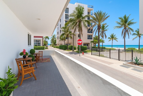 A hotel corridor with a stop sign, palm trees, and a view of the ocean.
