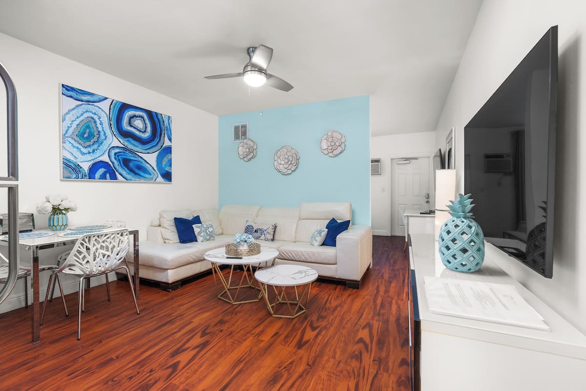 Un salon moderne avec un canapé blanc, deux tables basses et un ventilateur de plafond.