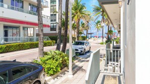 A hotel with a modern design, featuring a multi-story structure with balconies, palm trees, and a clear view of the street.